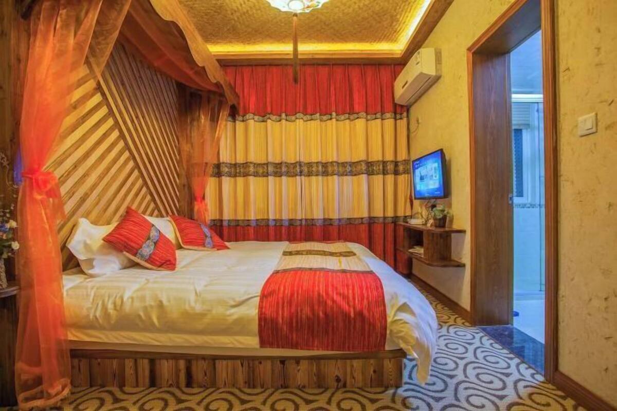 A bed with a canopy, a television on a stand, and a patterned carpet.