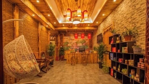 Ein gemütliches Interieur mit Holzbalkendecke, einem Hängesessel, einer Bar und Regalen mit diversen Gegenständen.