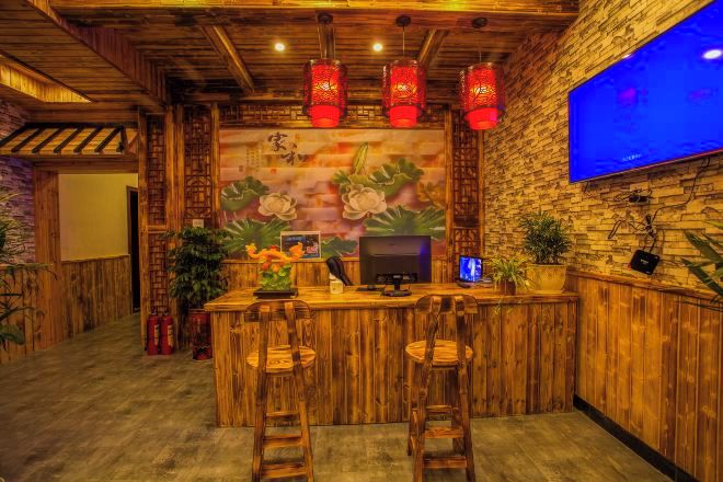 Zona de bar con mobiliario de madera, un televisor montado en la pared y faroles rojos.