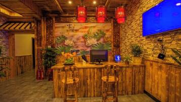 Zona de bar con mobiliario de madera, un televisor montado en la pared y faroles rojos.