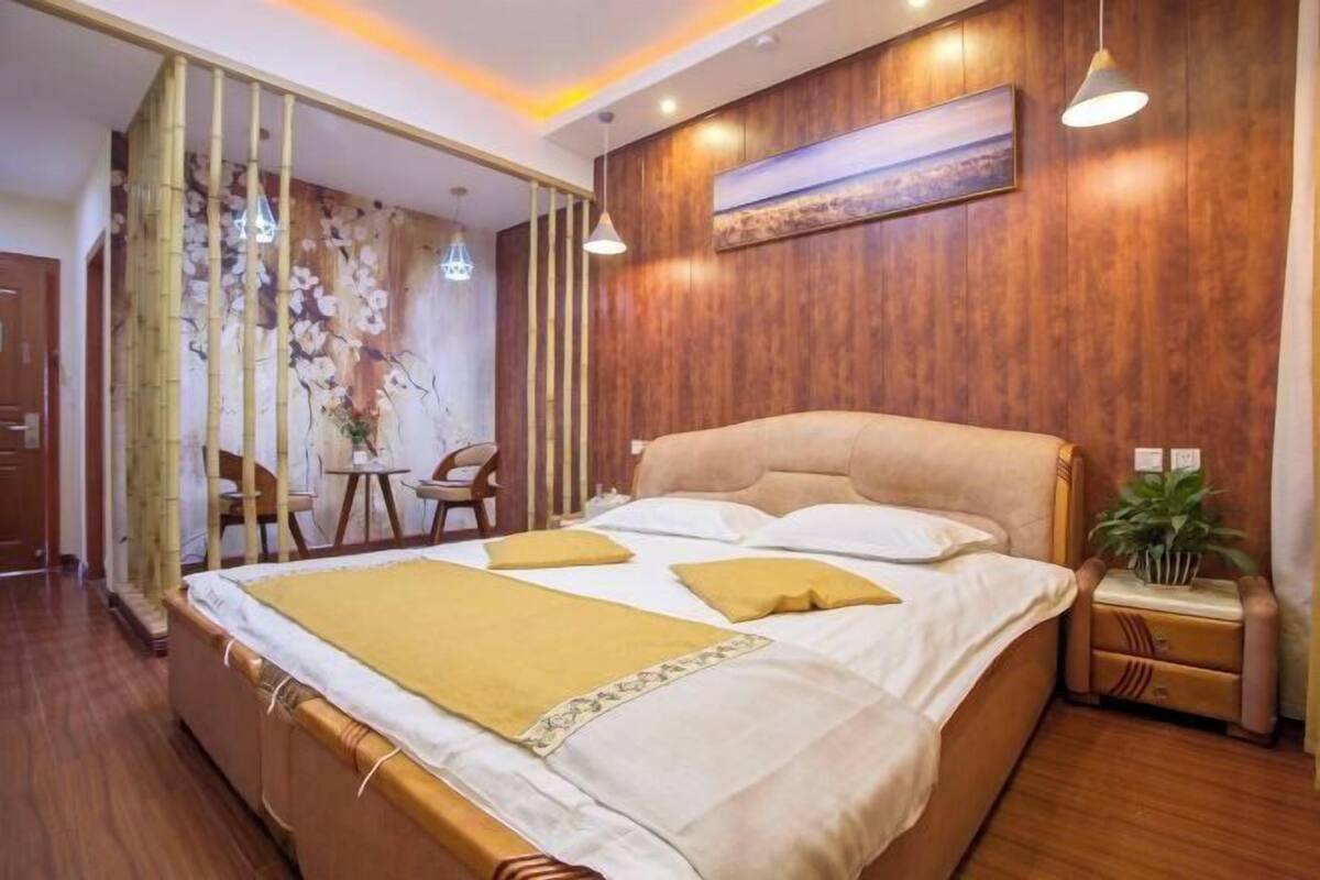 A bedroom with a bed, bedside tables, a mirror, and a wooden wall.