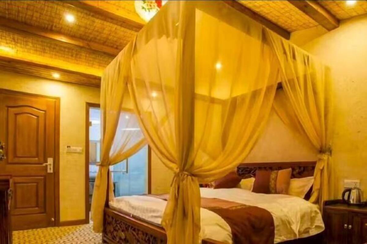 A room with a four-poster bed, wooden ceiling, and a window with a view.