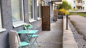 Un patio con una mesa y sillas, una cerca de madera y un camino que lleva a un edificio.