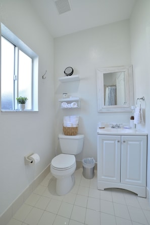 Bathroom features a toilet, sink, and mirror, with a small window for natural light.