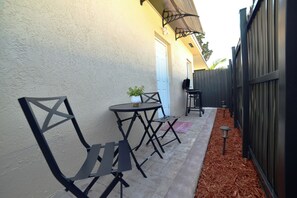 Enjoy a peaceful moment on the patio with a small table and chairs, surrounded by lush greenery.