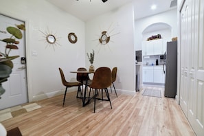 Enjoy meals in this dining area with a central table and four chairs, surrounded by decorative mirrors and a potted plant.