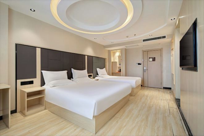 A modern hotel room with two beds, a TV, and a circular ceiling design.