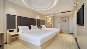 A modern hotel room with two beds, a TV, and a circular ceiling design.
