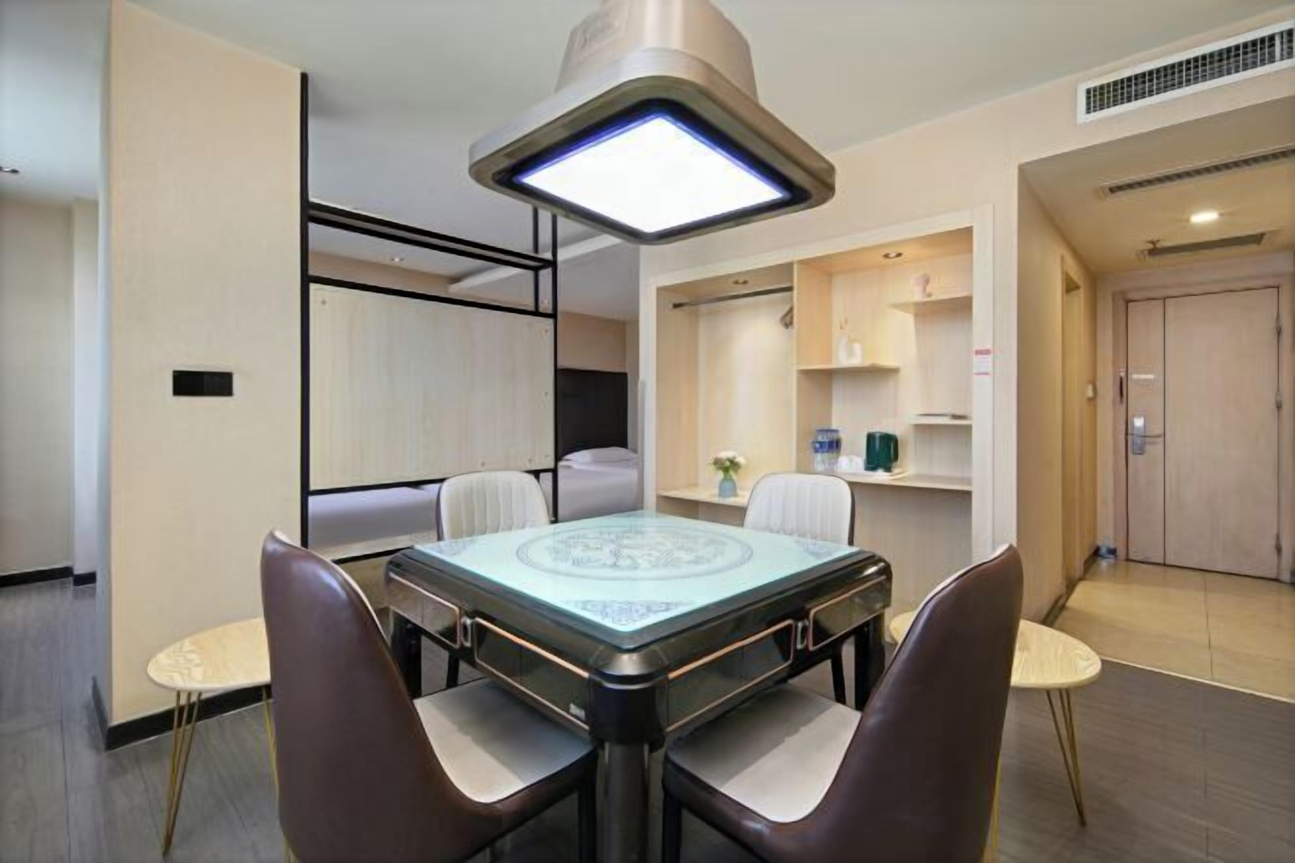 A modern dining area with a glass-top table, cushioned chairs, and a pendant light.