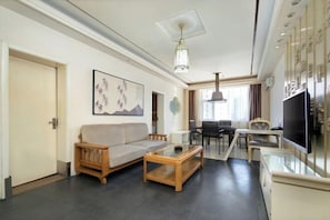 Una sala de estar moderna con sofá, mesa de centro y televisor. Hay un comedor con sillas y una mesa.