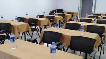 A conference room with tables and chairs, water bottles on tables, and a door in the background.