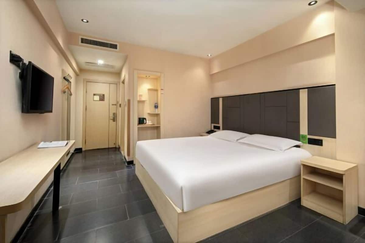 Una habitación de hotel con una cama grande, un escritorio, un televisor y un armario.