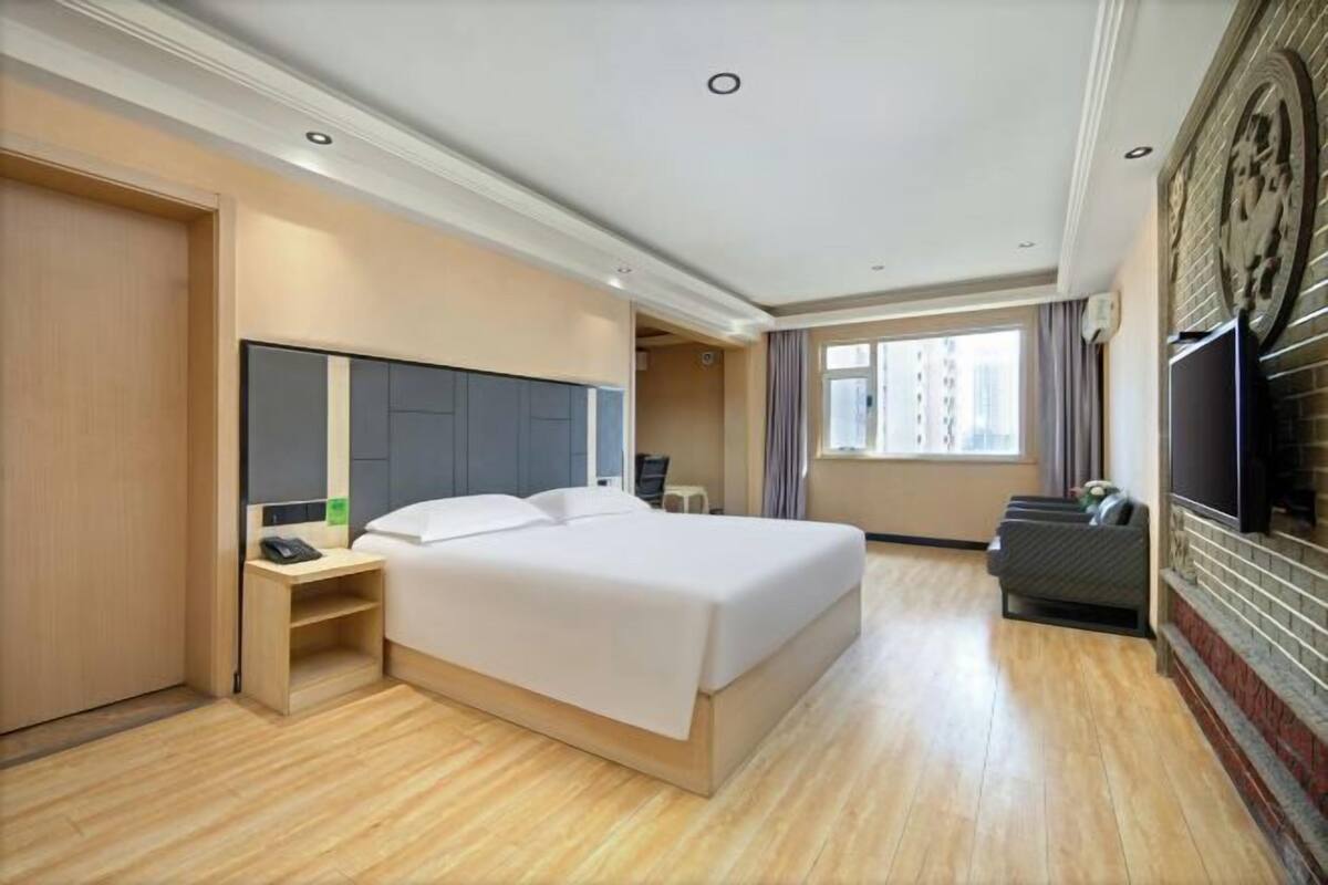 Una habitación de hotel con cama, mesita de noche, televisor y chimenea.