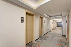 A hotel corridor with doors, carpeted flooring, and ceiling lights. - New Tangji Hotel (Taiyuan South Neihuan Street Jianshe South Road) (Taiyuan)