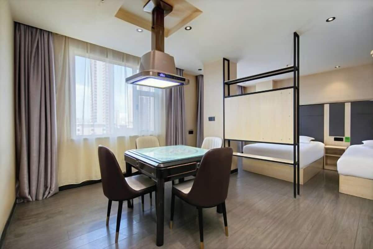 Una habitación de hotel con literas, una mesa de comedor con sillas y un ventanal con cortinas.