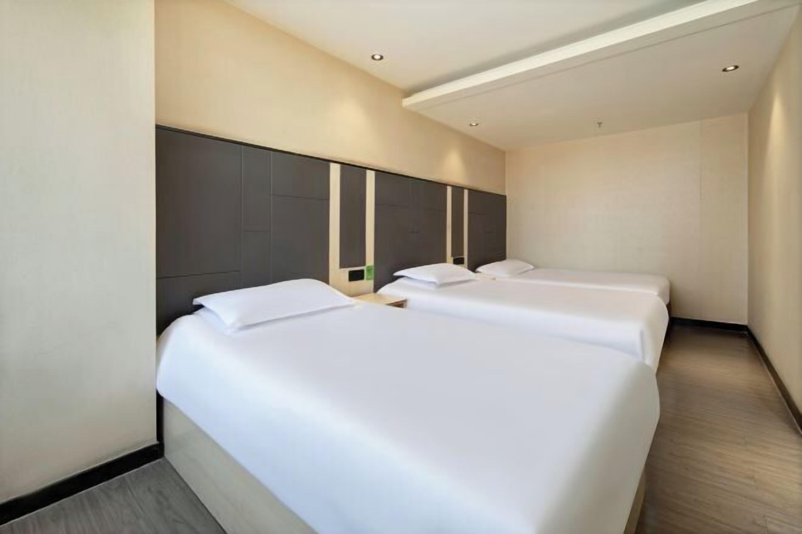 Een hotelkamer met twee eenpersoonsbedden, een modern hoofdeinde en een neutraal kleurenschema.