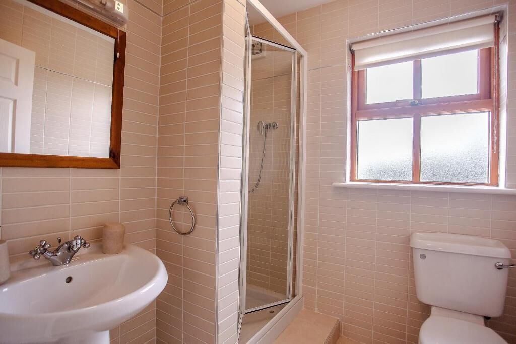 A bathroom with a white sink, a glass-enclosed shower, and a toilet.