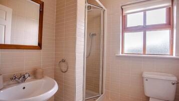 A bathroom with a white sink, a glass-enclosed shower, and a toilet.