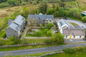 A traditional stone house with a thatched roof, surrounded by a well-maintained garden and a stone wall. - Burren Court Lodge (Ballyvaughan)