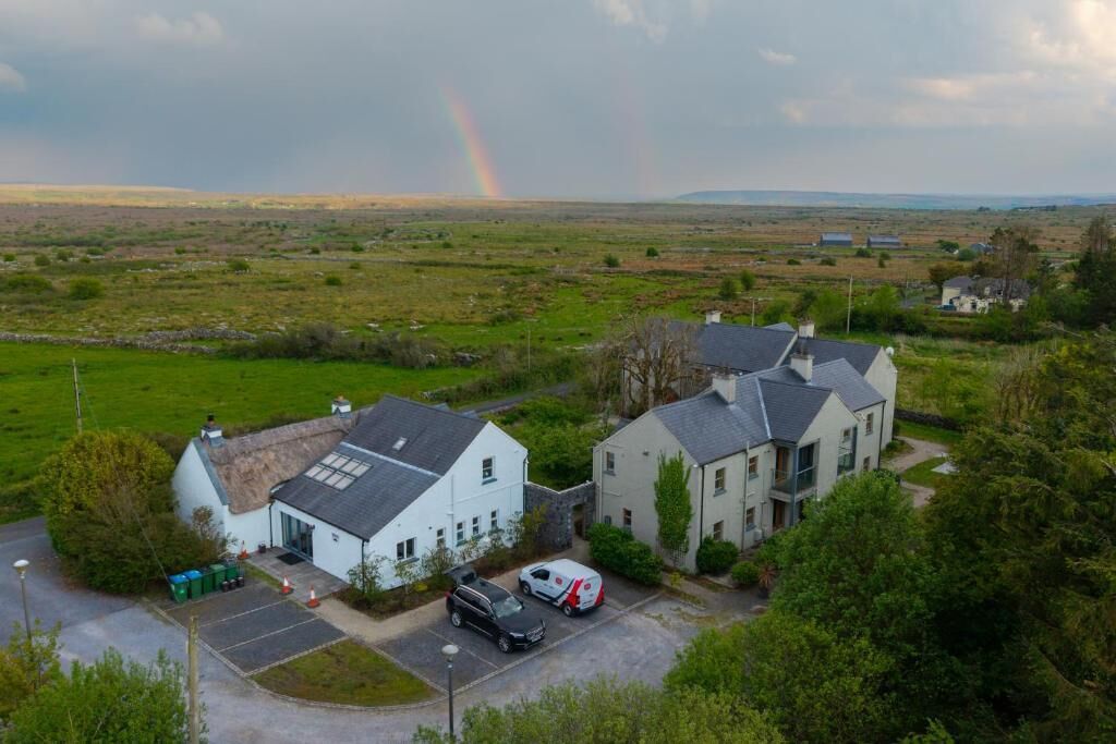 Un paysage rural avec une maison et une voiture garée dans l’allée.