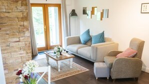 A living room with a stone wall, a sofa, a coffee table, and a chair. - Burren Court Lodge (Ballyvaughan)