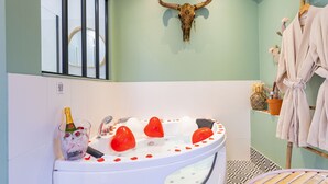 Ein Badezimmer mit einer runden Badewanne, einer Stierkopf-Dekoration, einer Champagnerflasche und einem Bademantelständer.