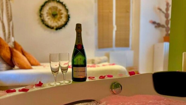 Un bain à remous avec une bouteille de champagne et deux verres sur une table.
