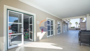 A hotel corridor with glass doors leading to rooms, a seating area with chairs, and a sign for 'Sala de Jogos'. - 45 (Portimão)