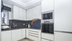 A modern kitchen with white cabinets, a built-in oven, and a window. - 45 (Portimão)