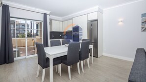 A modern apartment with a dining area, kitchen, and a balcony with a view of buildings. - 45 (Portimão)