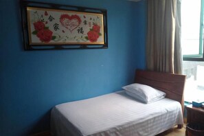 A single bed with a wooden headboard in a room with blue walls. - Chashan Hostel (Shanghai)