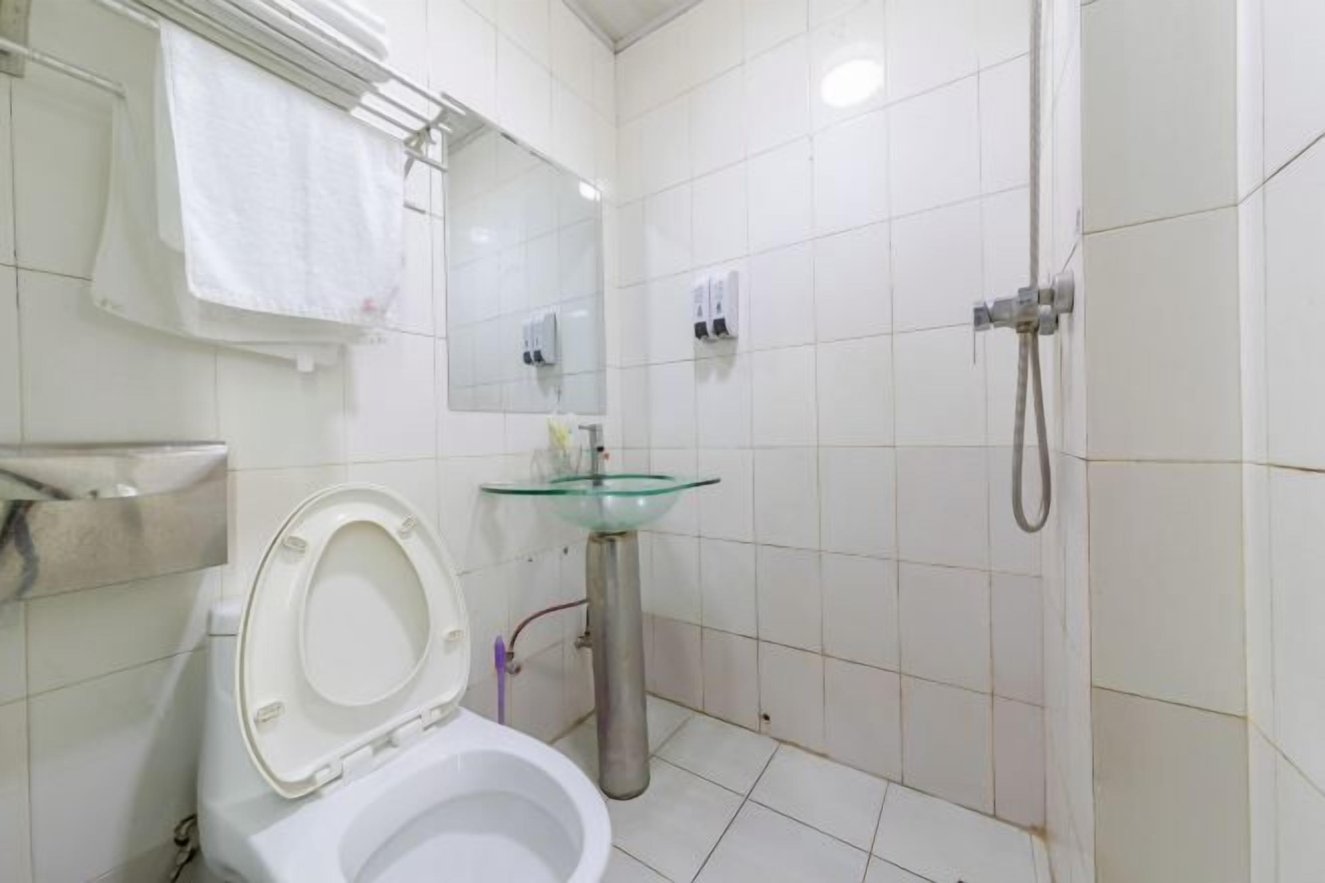 A bathroom with a toilet, a glass sink, a shower, and a mirror.
