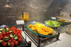 A buffet with various fruits and vegetables, including tomatoes and oranges, displayed on a marble countertop. - Manju Hotel Railway Station Jinhua (Jinhua)