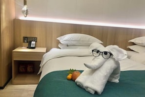 A hotel room with a bed, a nightstand with a phone, and a towel shaped like an elephant. - Manju Hotel Railway Station Jinhua (Jinhua)
