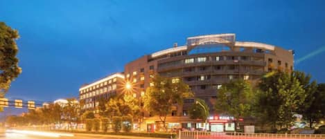 A modern hotel with multiple floors, a curved facade, and a well-lit entrance.