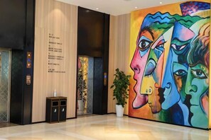 Un vestíbulo con un cuadro abstracto de gran tamaño, una recepción y una planta en maceta.