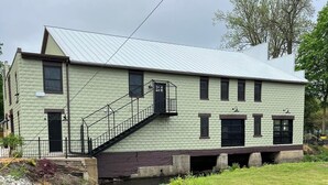A two-story building with a metal roof, a staircase leading to the upper floor, and a small front porch. - The Grant Hotel and Venue (Buchanan)