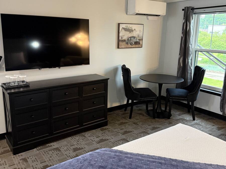 A hotel room with a bed, a TV, a desk, and a chair.