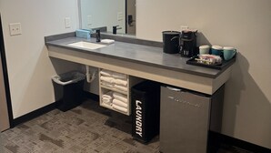 A modern bathroom with a large mirror, a sink, a coffee machine, and a trash bin. - The Grant Hotel and Venue (Buchanan)