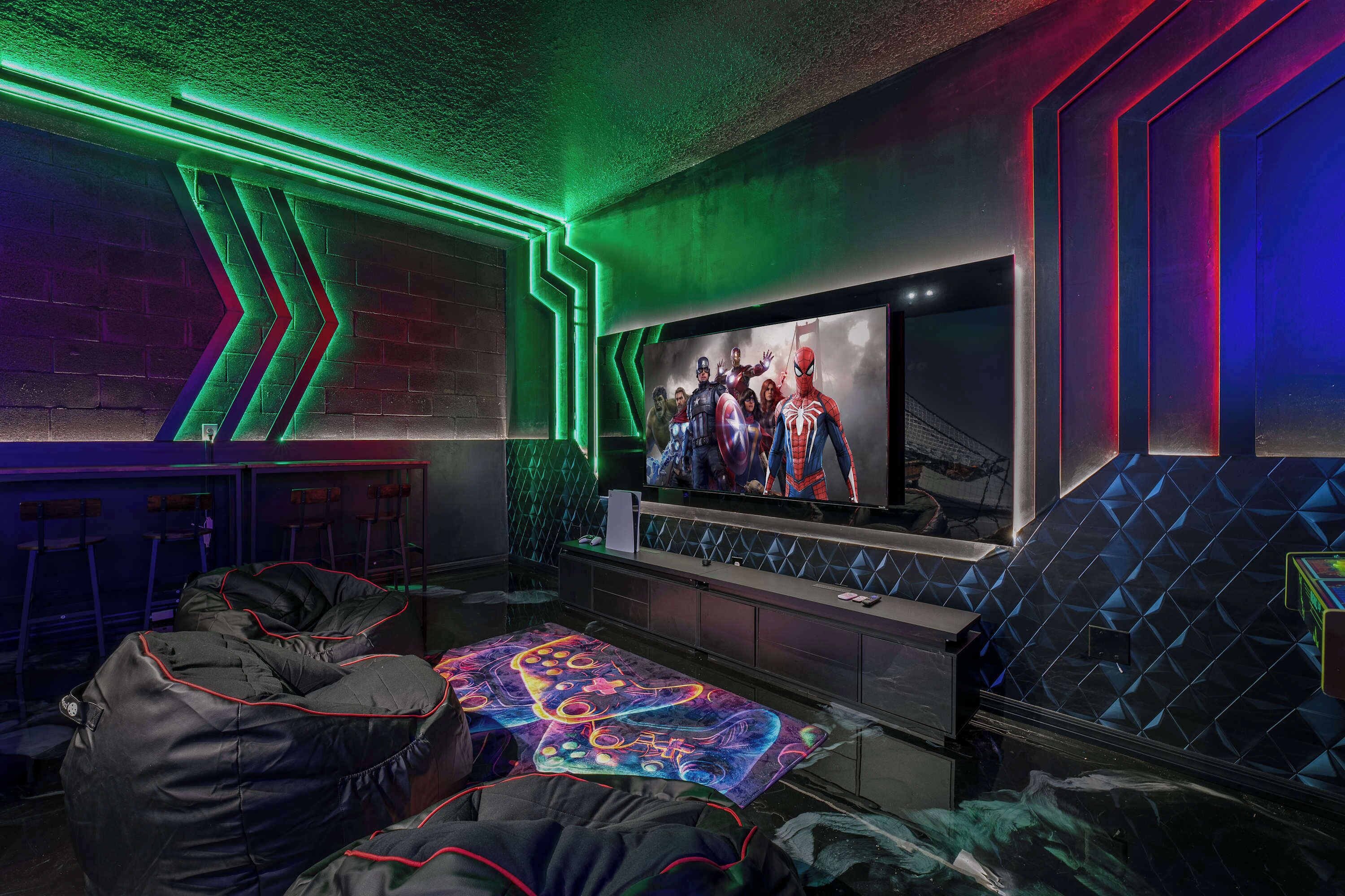 A gaming room with a large TV, bean bag seating, and neon lighting.
