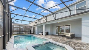 A pool area with a glass-enclosed patio, a hot tub, and outdoor seating. - Super Homey (Clermont)