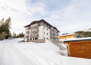 A multi-story building with balconies, a ski slope in the foreground, and a mountainous backdrop. - Penthouse in Katschberghohe Near Ski Slopes (Rennweg am Katschberg)