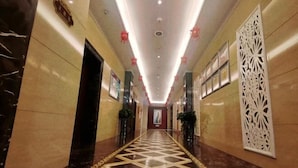 A hotel corridor with a patterned floor, decorative wall panels, and a ceiling with recessed lighting. - Dunhuang Carnival International Hotel (Shazhou Night Market) (Dunhuang)