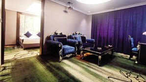 A hotel room with a bed, two armchairs, a coffee table, and a desk. - Dunhuang Carnival International Hotel (Shazhou Night Market) (Dunhuang)