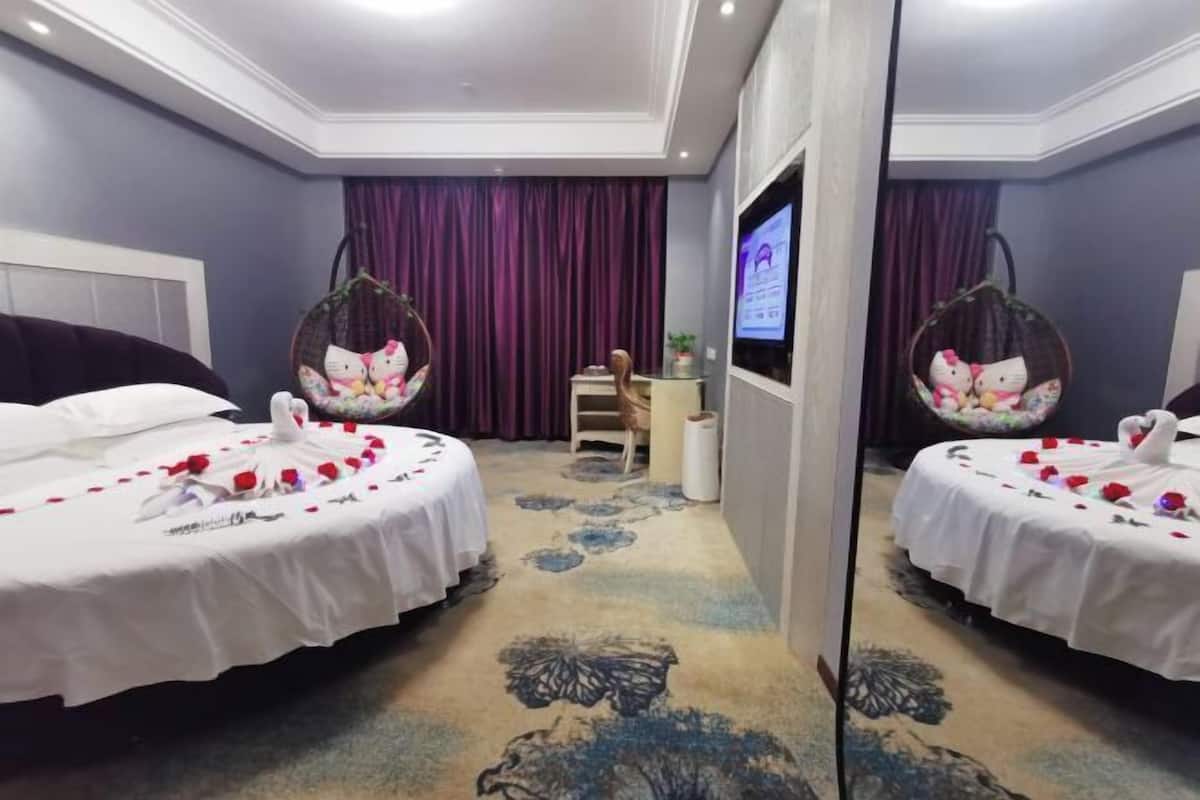 A hotel room with two beds, a TV, a mirror, and a decorative wall.