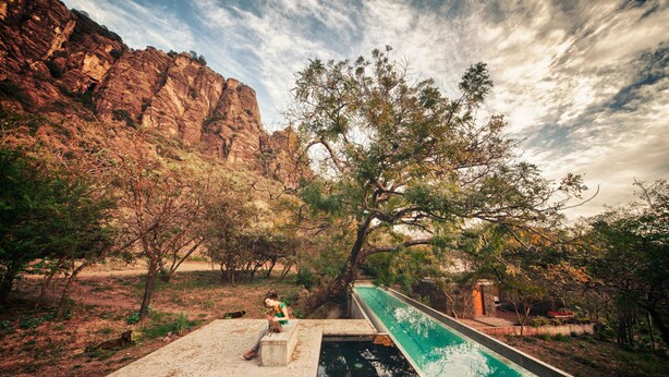 Una piscina con vistas a acantilados rocosos y vegetación escasa.