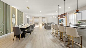 A modern kitchen with a central island, bar stools, and pendant lighting. - Super Play (Kissimmee)