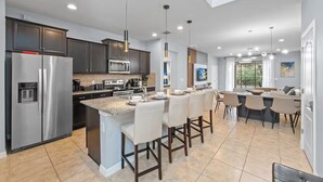 A modern kitchen with dark cabinets, stainless steel appliances, and a central island with bar stools. - FL- 1844 GOBI DR (Kissimmee)
