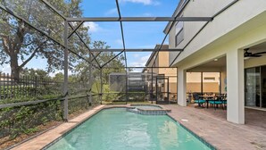 A swimming pool with a glass enclosure, surrounded by a patio area with outdoor furniture. - FL- 1844 GOBI DR (Kissimmee)