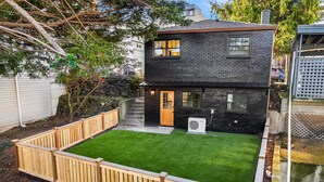 A two-story black brick house with a wooden deck and a well-maintained lawn. - Queen Anne City Escape - 1 bed, 1.5 bath, dog friendly, 1 parking space (Seattle)